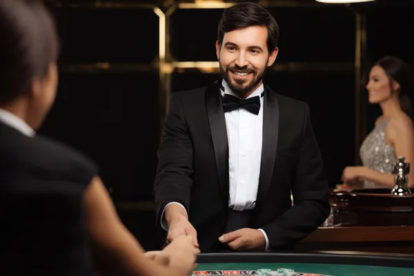 A woman in a luxurious green gown next to an ornate roulette wheel, capturing the upscale casino mood of BA99.